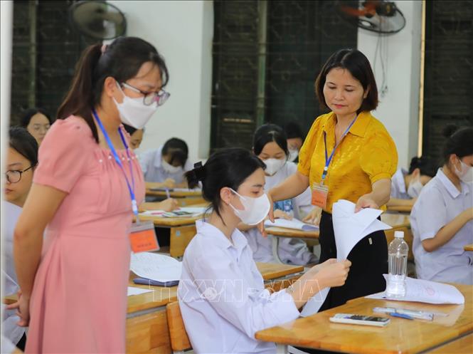 Cán bộ coi thi phát giấy thi cho thí sinh điểm thi Trường THPT Đan Phượng trước giờ thi Toán. Ảnh: Hoàng Hiếu - TTXVN 